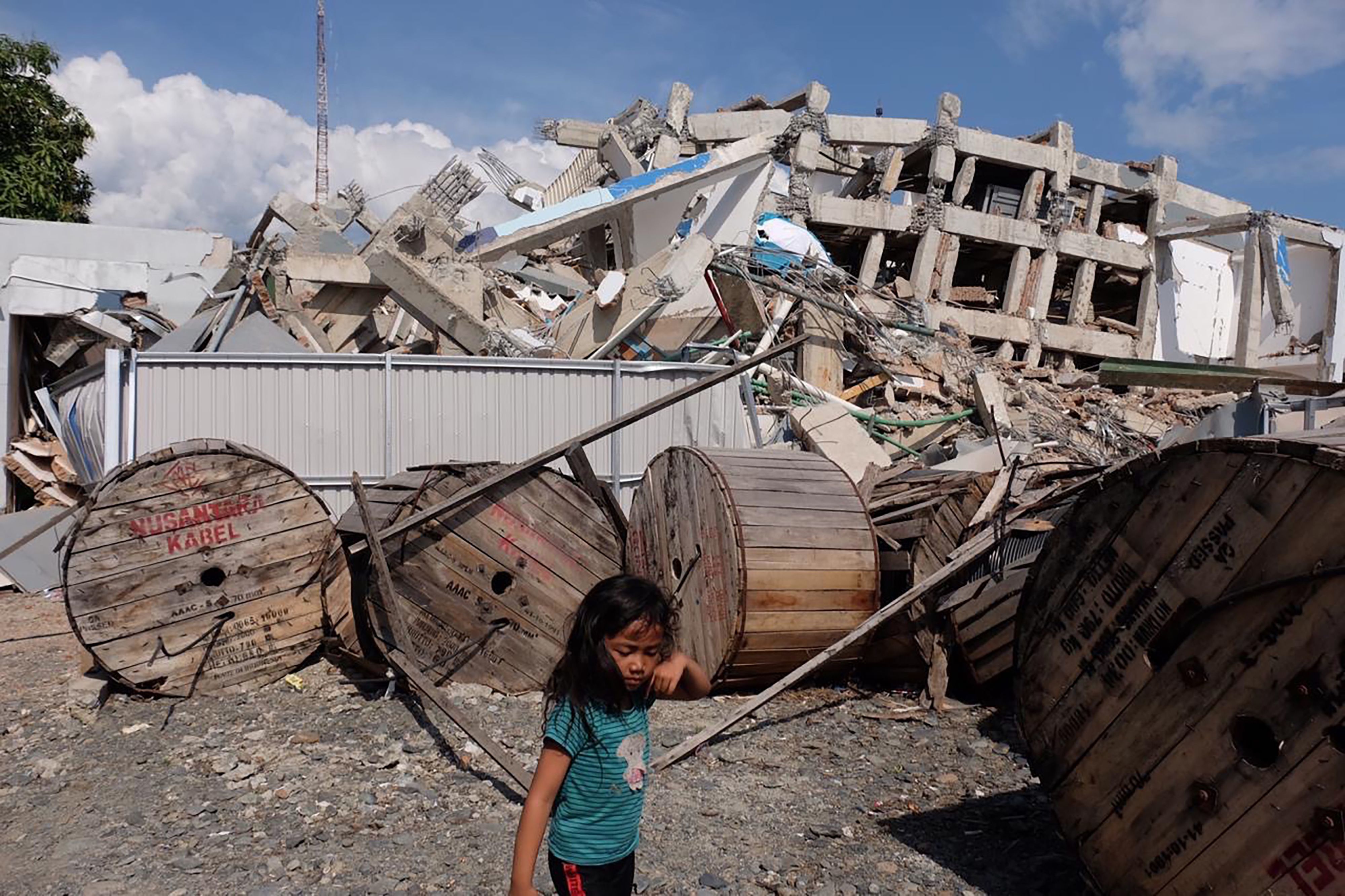 Una niña camina entre los escombros de un edificio en indonesia.