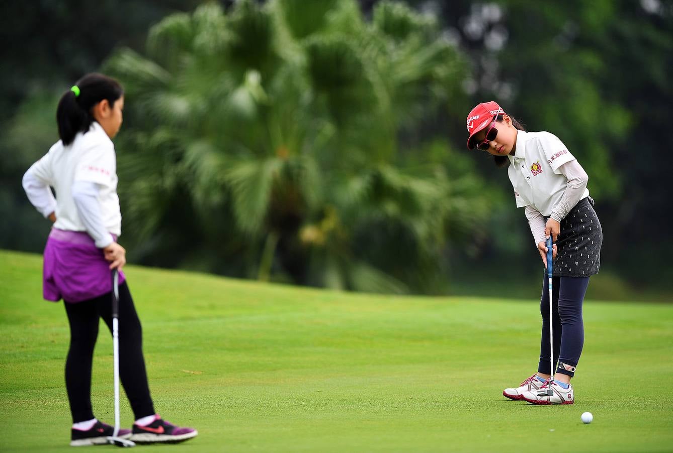 La Asociación China de Golf tenía 400 jugadores juveniles registrados en 2013, el año pasado eran 35.000 y se espera que en un lustro la cifra ronde los 100.000. Lai Runci, de 6 años, y Lai Yiyan, de 9 (protagonistas en la mayoría de las fotos), participan en un torneo para niños en Dragon Lake Golf Club en, Guangzhou. Ambos representan al ejército de jóvenes golfistas de China y el interés creciente del país por un juego que estuvo prohibido bajo el mandato de Mao Zedong porque era «para millonarios...»