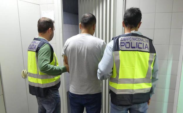 Dos agentes custodian al individuo reclamado por la Justicia.