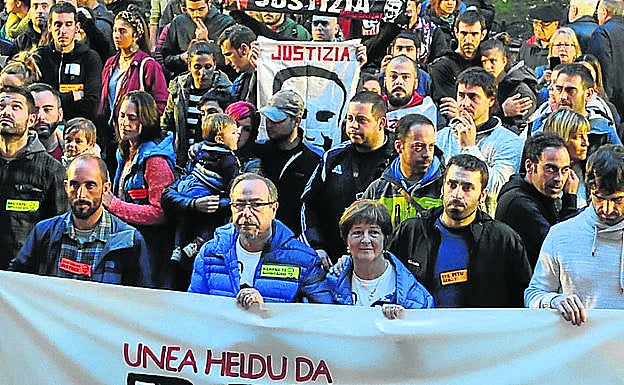 Los padres del joven, tras la pancarta en recuerdo a su hijo.