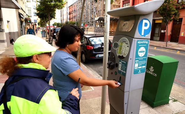 Una conductora extrae un ticket de la ORA en un parquímetro, junto a una de la revisoras del servicio. 