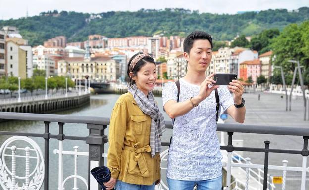 Dos turistas se fotografían en el puente de El Arenal en Bilbao.