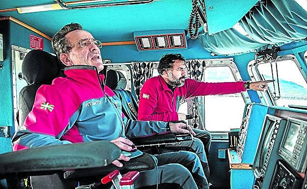 Imagen principal - Tito López es el patrón de la embarcación de rescate 'Itsas Zain'. En la imagen de arriba a la izquierda, dirige la maniobra para salir del Abra. Abajo, en el camarote, consultando la carta de navegación correspondiente al fondeadero de Matxitxako. Abajo, Josean Sánchez, mecánico, lleva nueve años asignadoa la embarcación. Observael panel de instrumentos mientras al otro lado del portillo se dibuja la plataforma de gas 'Gaviota'.