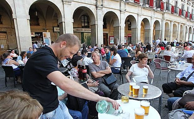 Un camarero sirve unas bebidas en una terraza en Vitoria. 
