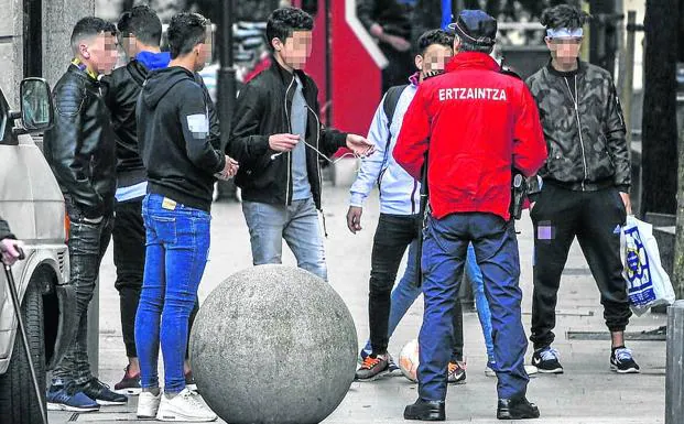Un agente de la Ertzaintza identifica a un grupo de 'menas' en el centro de Bilbao. 
