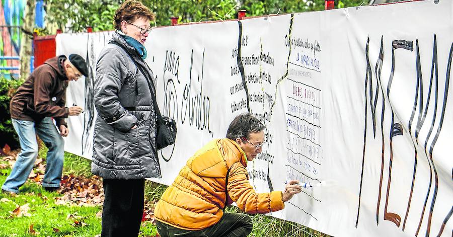 Varias personas realizan sus aportaciones sobre la gran pancarta en torno a San Francisco de Asís.