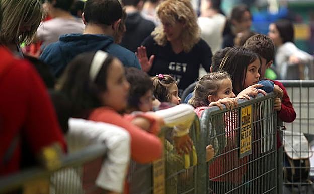 Niños y padres haciendo cola para montar en una barraca.