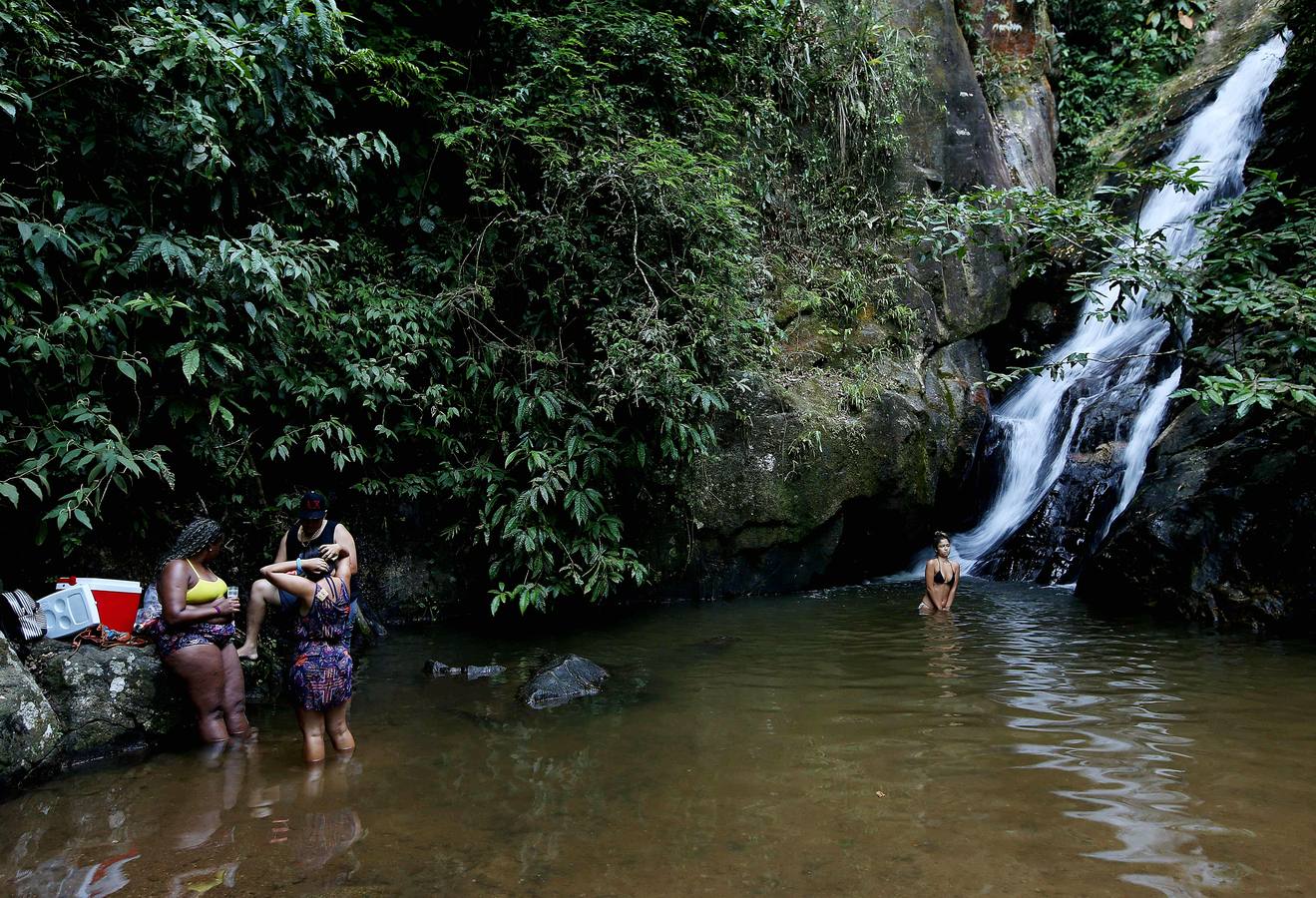 Hoy comienza el verano austral. Pero las playas de Río de Janeiro ya están llenas de bañistas desde hace unas semanas. Y es que el calor aprieta. El martes los termómetros alcanzaron 40,7 grados en la zona oeste de la ciudad, en el que ha sido el día más caluroso en varios años, con una sensación térmica de 45 grados. El mar está calmado y apenas hay olas en las transparentes aguas. Las imágenes han sido tomadas en la Floresta de Tijuca, el bosque urbano más grande del mundo, y en los arenales del oeste de Río.