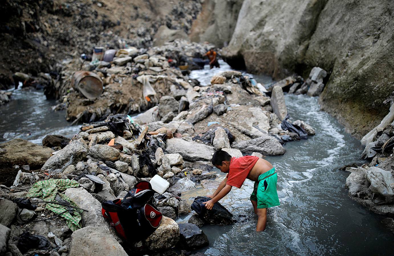 'La Mina', en la ciudad de Guatemala, se encuentra al fondo de un barranco atravesado por un río. Centenares de personas se afanan cada día entre sus aguas contaminadas, bajo la amenaza de deslizamientos y enfermedades, para tratar de encontrar objetos o chatarra con la que ganarse la vida. Algunos utilizan imanes para atraparlos, otros lo hacen a mano, introduciendo su cuerpo directamente en el agua, convertida en basurero. Si hay suerte pueden conseguir unos 20 dólares, el doble del salario mínimo. En ocasiones hasta es posible hallar un anillo o un pendiente de oro.