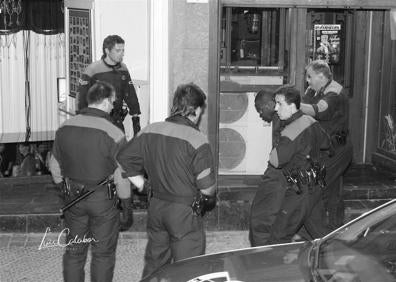 Imagen secundaria 1 - Imágenes de la puerta del local y del detenido, custodiado por varios agentes.