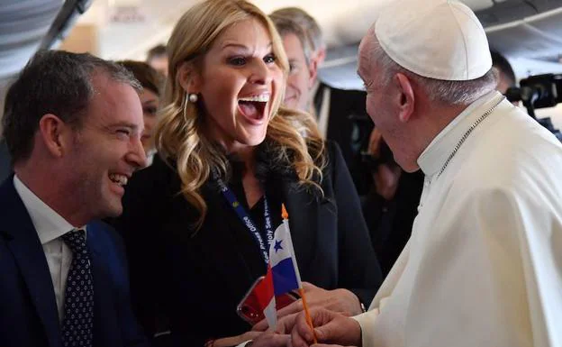 El papa Francisco (d) ondea una bandera panameña junto a los periodistas que viajan con él en el avión. 
