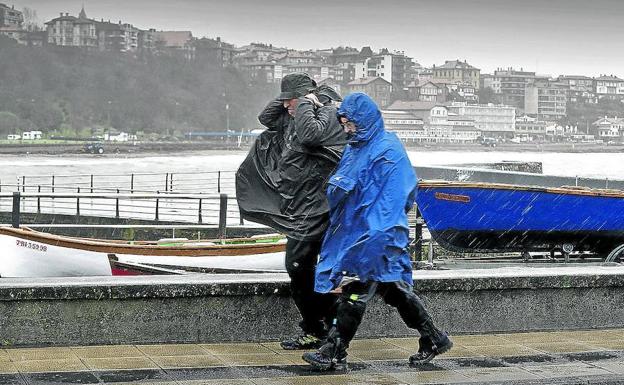 Dos personas se protegen de la lluvia y el viento, ayer, en el Puerto Viejo de Algorta.