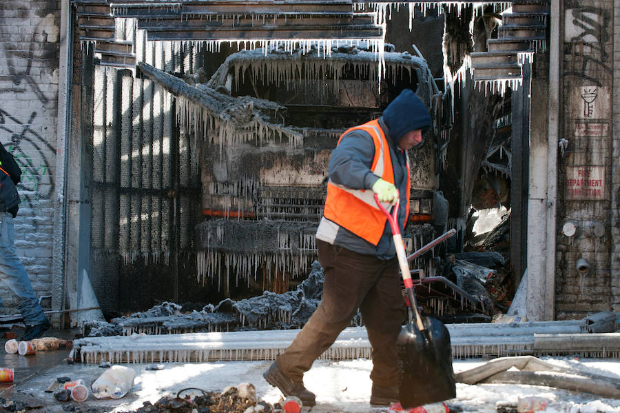 Un operario trabaja para retirar el hielo formado después de un incendio en Brooklin, Nueva York