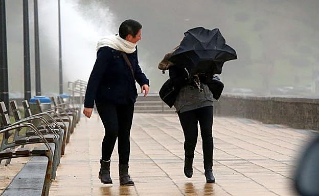 Dos mujeres luchan contra el viento en la playa de Ereaga de Getxo. 