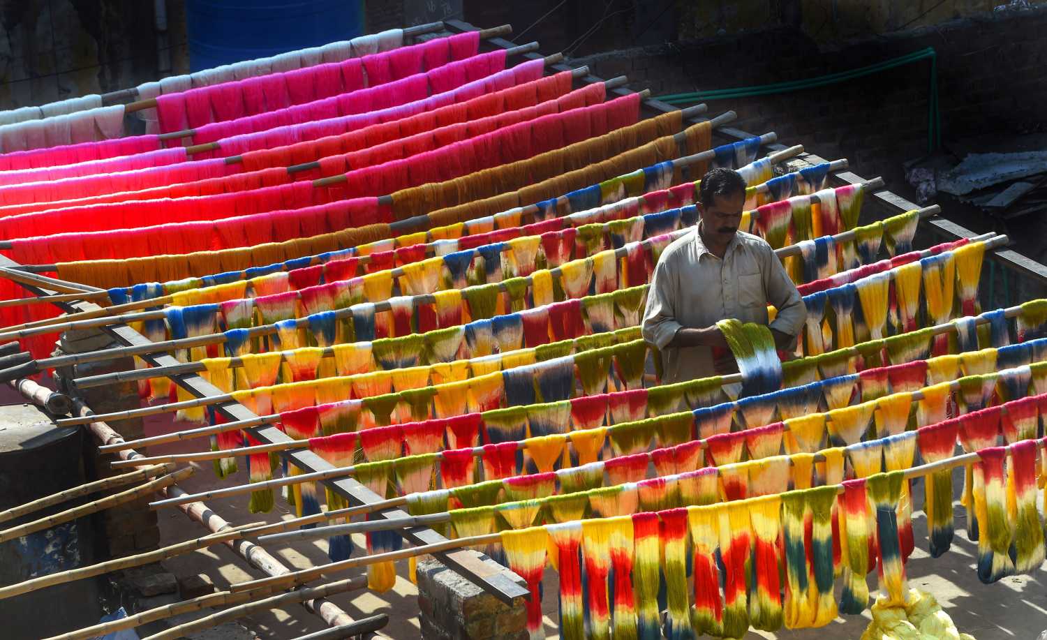 Trabajador paquistaní seca al aire libre unas telas tintadas, en Lahore