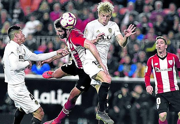 Raúl García busca un complicado remate ante la oposición de Wass y la vigilancia de Roncaglia.