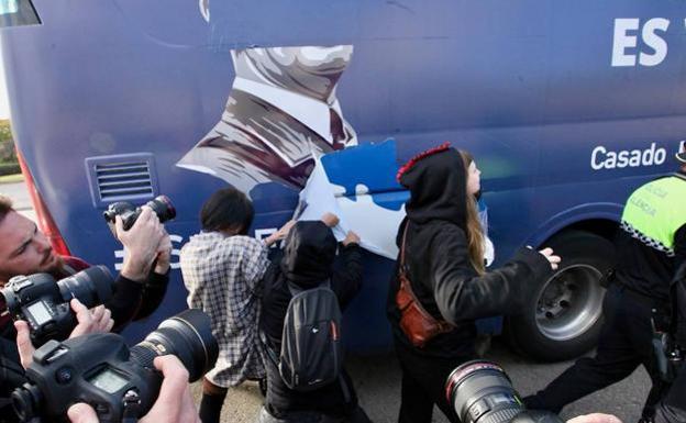 Un grupo de jóvenes arranca por la fuerza los vinilos del autobús.
