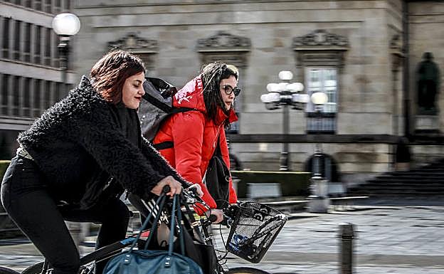 Dos chicas, en bici por Vitoria. 