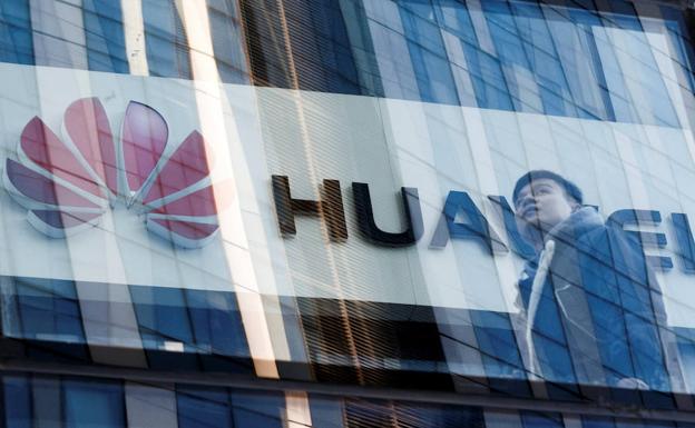 Un hombre camina frente a una tienda de Huawei en Pekín.