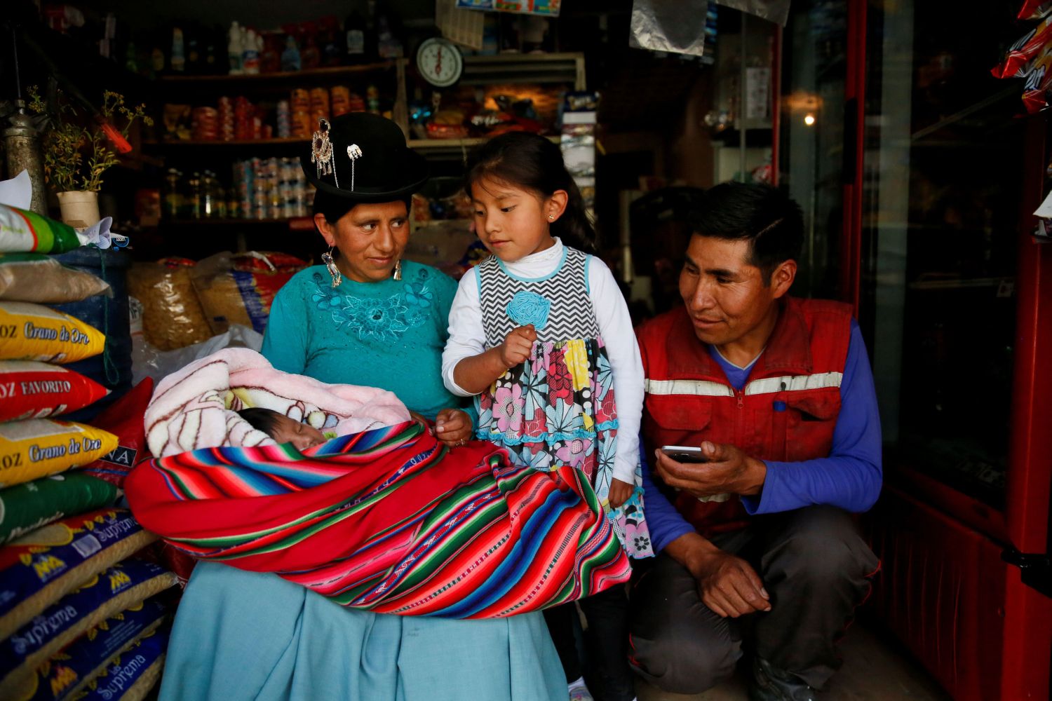 Ana Huanca, de 34 años, su bebé Luciana de seis semanas, su hija mayor Anabel, de 5 años, y su esposo Luis Quaquira, de 44 años, posan para una fotografía en su tienda de alimentos en La Paz, Bolivia, el 26 de febrero de 2019. En Bolivia, las madres tienen derecho a 15 días de licencia por maternidad antes de dar a luz y 45 días después de haber dado a luz. Los padres tienen derecho a tres días. Sin embargo, Ana y Luis se encuentran entre la mayoría de los trabajadores bolivianos que no tienen empleos regulares -que les darían derecho a prestaciones como la licencia de maternidad-. Huanca volvió al trabajo dos semanas después de dar a luz y ella misma cuida a la bebé mientras trabaja. "Me sentí bien, fue un parto normal y ella nació sana", dijo sobre su regreso al trabajo tan pronto, después de dar a luz. Luis, que trabaja como mecánico, de forma independiente, no se despidió: "La única licencia que me concedí fue el día en que nació mi hija", dijo