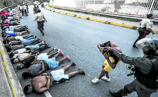 Las fuerzas de seguridad vigilan a un grupo de arrestados a los que mantienen tendidos en una carretera en Caracas.