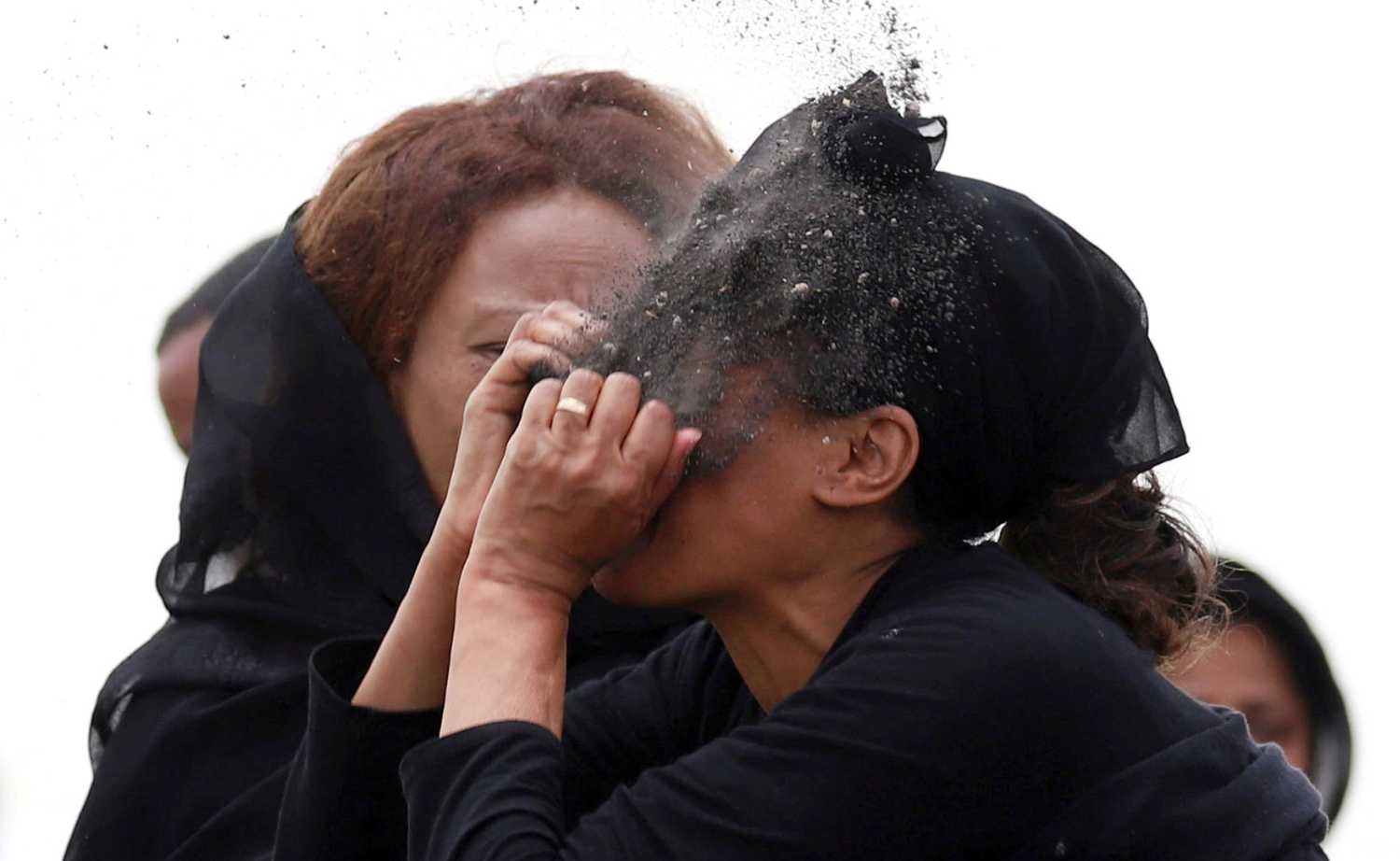 Familiar de una de las victimas del accidente aéreo del vuelo ET 302 de Ethiopian Airlines, se arroja tierra a la cara mientras llora en el lugar del accidente, en Addis Ababa, Etiopia