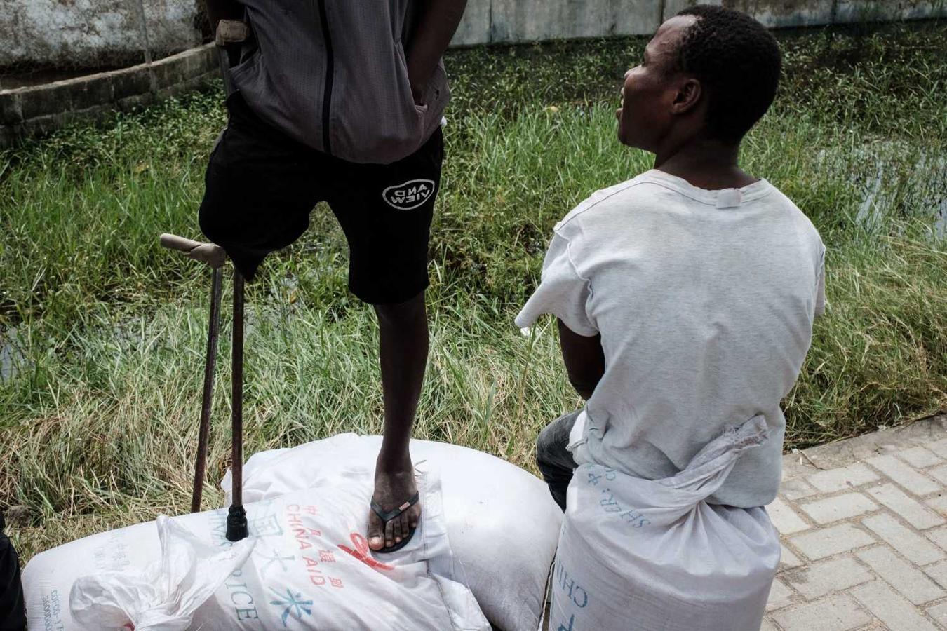 Un hombre, con una pierna amputada, habla con un conocido en una zona de reparto de alimentos tras el paso del ciclón tropical Idai en Mozambique