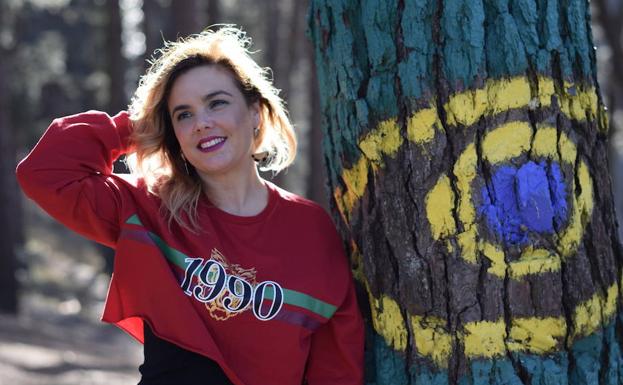 Vanessa Mulas posa con una sudadera de H&M junto a un árbol pintado del bosque de Oma.