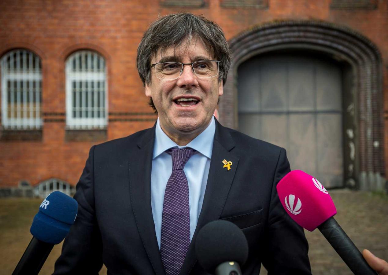 El expresidente de la Generalitat Carles Puigdemont (c) hace una declaración a la prensa a las puertas de la prisión de Neumünster (Alemania), tras hacer una donación a la biblioteca de la institución. Puigdemont visita la cárcel exactamente un año después de ser detenido en Alemania e ingresar en ella, mientras se evaluaba la euroorden activada por la Justicia española por los cargos de rebelión y malversación de fondos