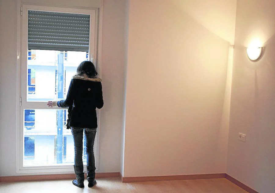 Una adjudicataria de un piso social mira por la ventana tras entrar por primera vez en la vivienda.
