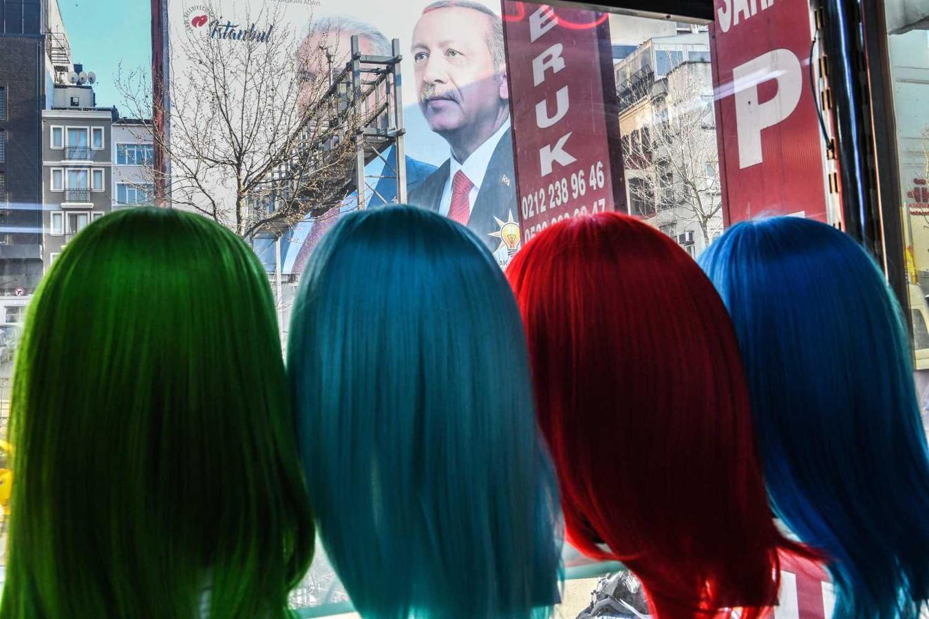 Un cartel gigante del presidente turco, Recep Tayyip Erdogan visto desde el escaparate de una tienda donde se exhiben modelos de pelucas, en Estambul