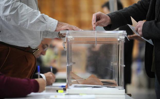 Una persona deposita su voto en una mesa electoral.