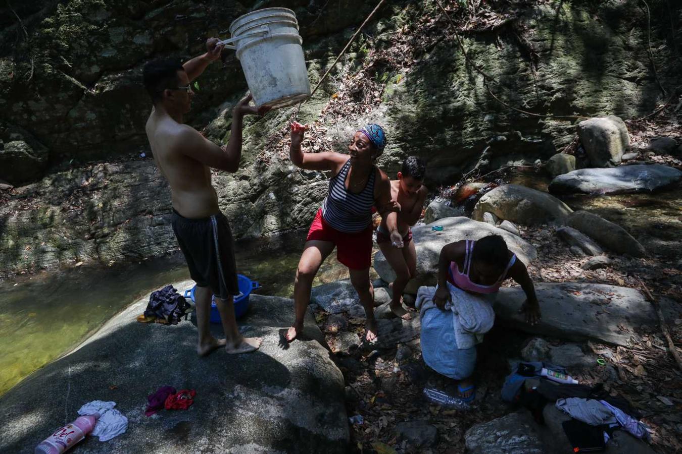 Personas lavan piezas de ropa en una quebrada de la montaña El Ávila, por los cortes de agua y luz en Caracas (Venezuela)