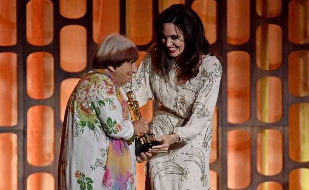 Imagen principal - Agnés Varda recibiendo el Oscar de manos de Angelina Jolie en 2017, en una exposición en 2011 y en una foto de juventud con Jim Morrison en París.