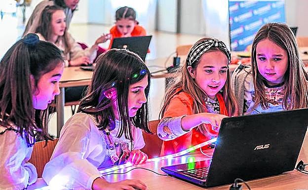 Varias niñas programan una tira de luces LED. 