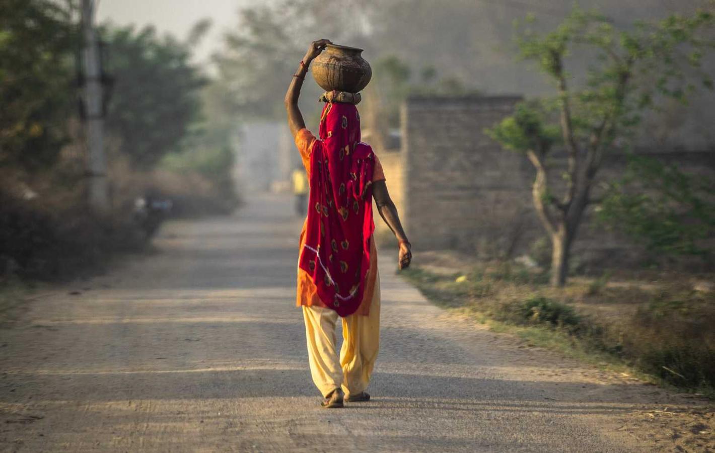 Una mujer india camina mientras sostiene una olla de barro sobre su cabeza en el estado de Haryana