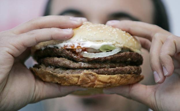 Un hombre se come una hamburguesa.