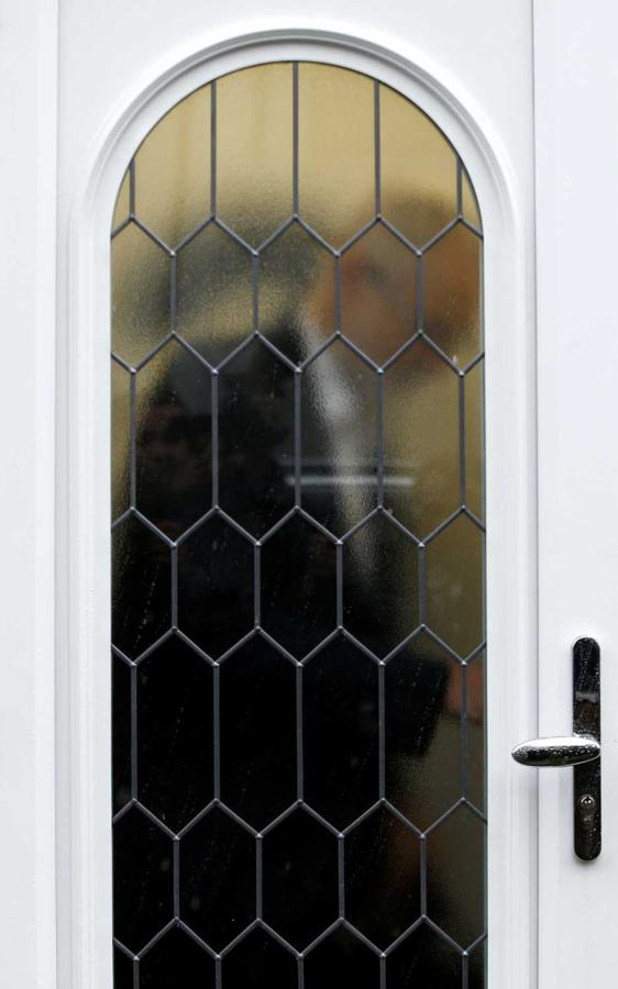 Jeremy Corbyn, líder de la oposición británica del Partido Laborista, es visto a través de una puerta de vidrio cuando sale de su casa en Londres