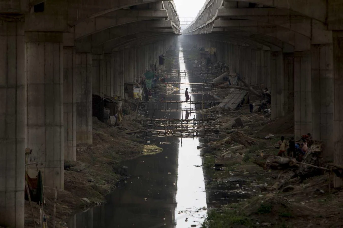 Una personas cruzando un puente improvisado sobre un canal de aguas residuales en Danapur, India