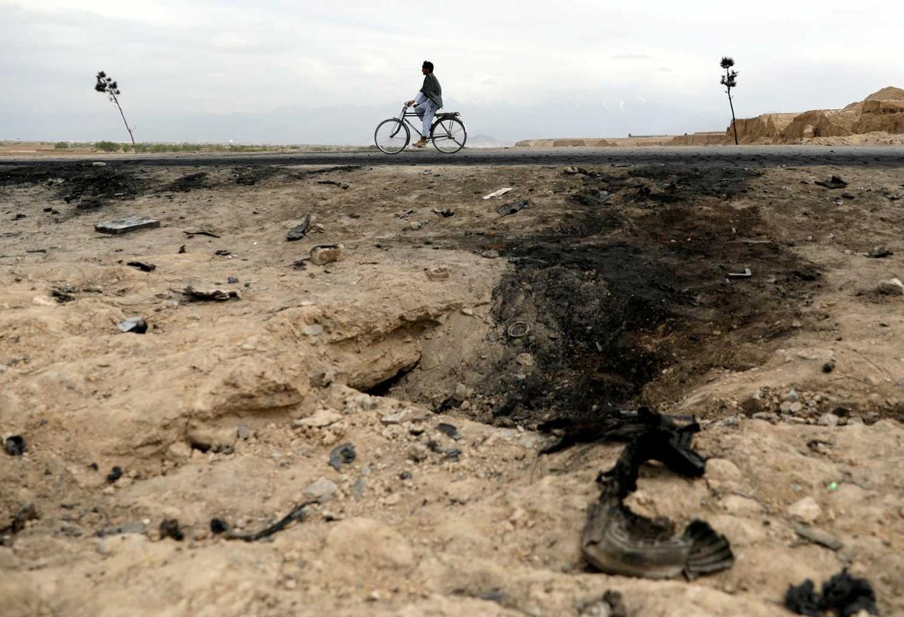 Un hombre afgano pasando en bicicleta junto al lugar donde varios soldados norteamericanos murieron en un ataque con coche bomba, cerca de la base aérea de Bagram Afganistán