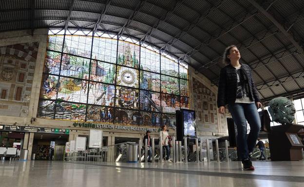 Viajeros pasan bajo la gran vidriera de la Estación de Abando. 