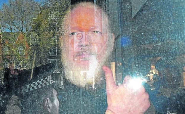 Julian Assange levanta el pulgar en el furgón policial en el que fue trasladado a comisaría, antes de ser puesto a disposición judicial. 