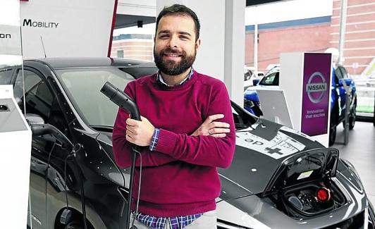 Asier Beltrán posa con el coche eléctrico que ha comprado. 