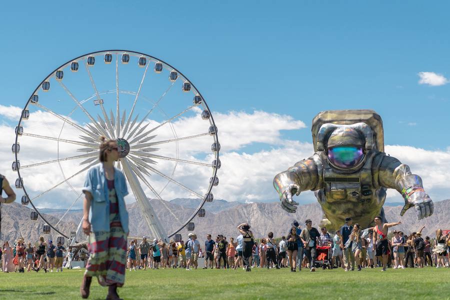 Los asistentes caminan frente a una enorme noria y la figura de un astronauta durante su asistencia al festival.