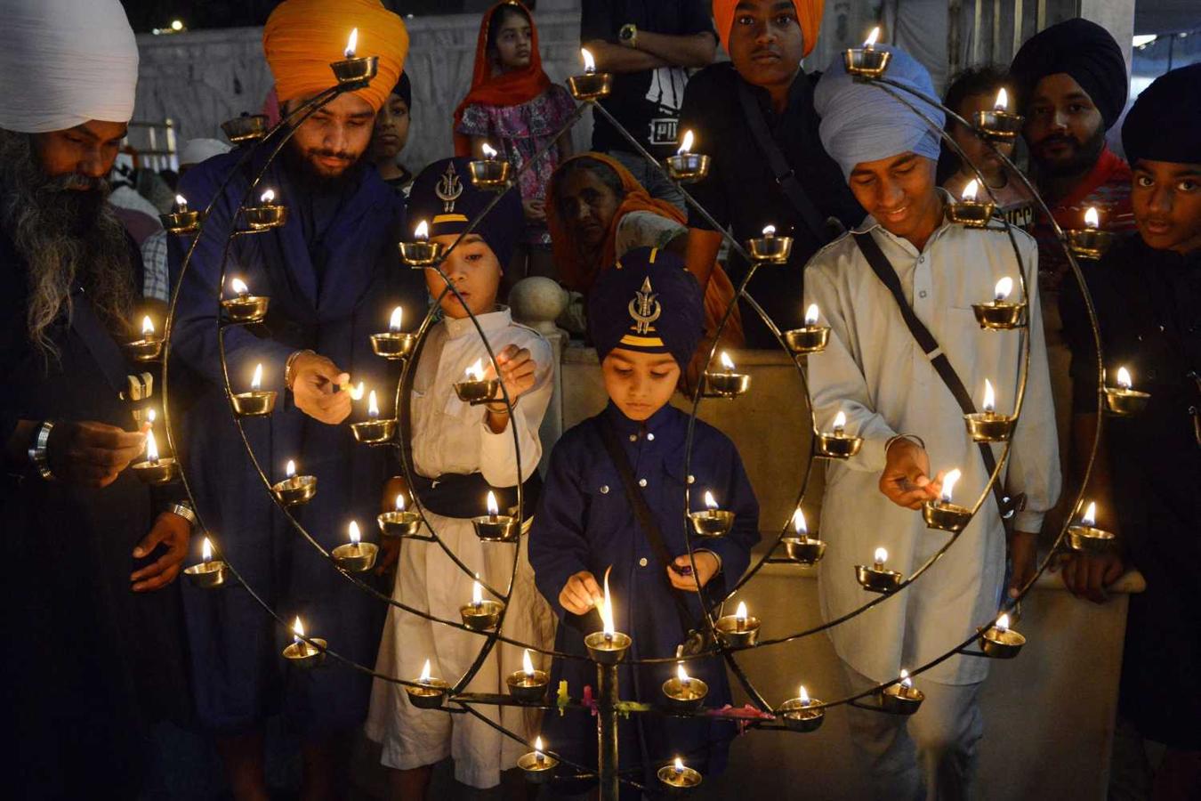Hombres de la comunidad sij encienden velas con motivo del festival Baisakhi en el Templo Dorado en Amritsar, India