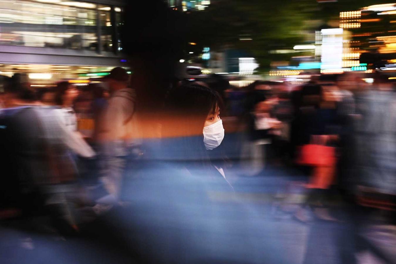 Una mujer protegida con una máscara en una calle del distrito de Shibuya en Tokio 