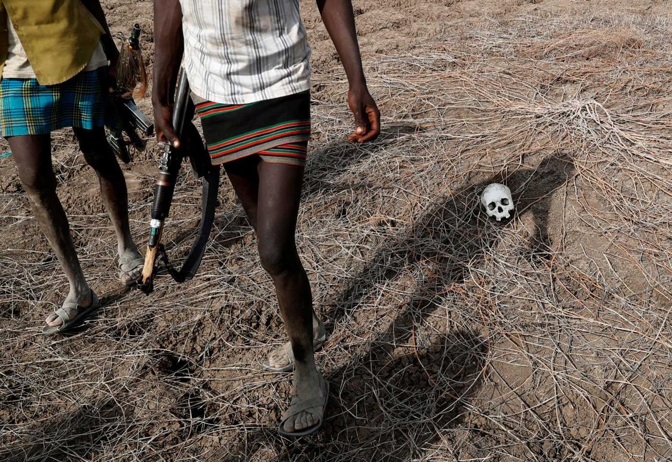 Dos guerreros de Turkana pasan junto a un cráneo de un hombre, en Kenia