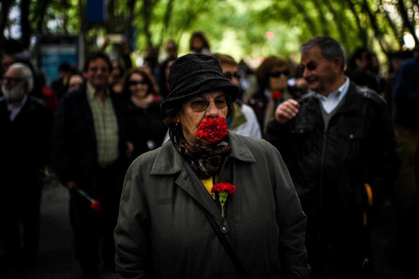 Una mujer camina con claveles rojos en su boca para conmemorar el 45 aniversario de la revolución de los claveles rojos de Portugal, en Lisboa 