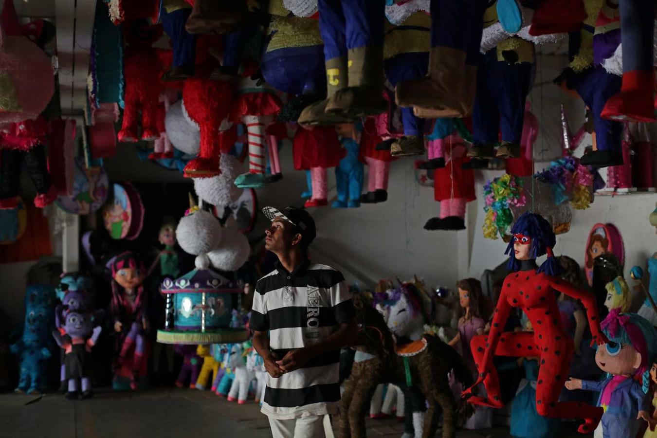 Un hombre mira las piñatas en una tienda de artículos para cumpleaños en Caracas, Venezuela. El gerente de la tienda dijo: "La gente venía después del trabajo o temprano los sábados a comprar artículos para cumpleaños. Ahora vienen pocas personas".