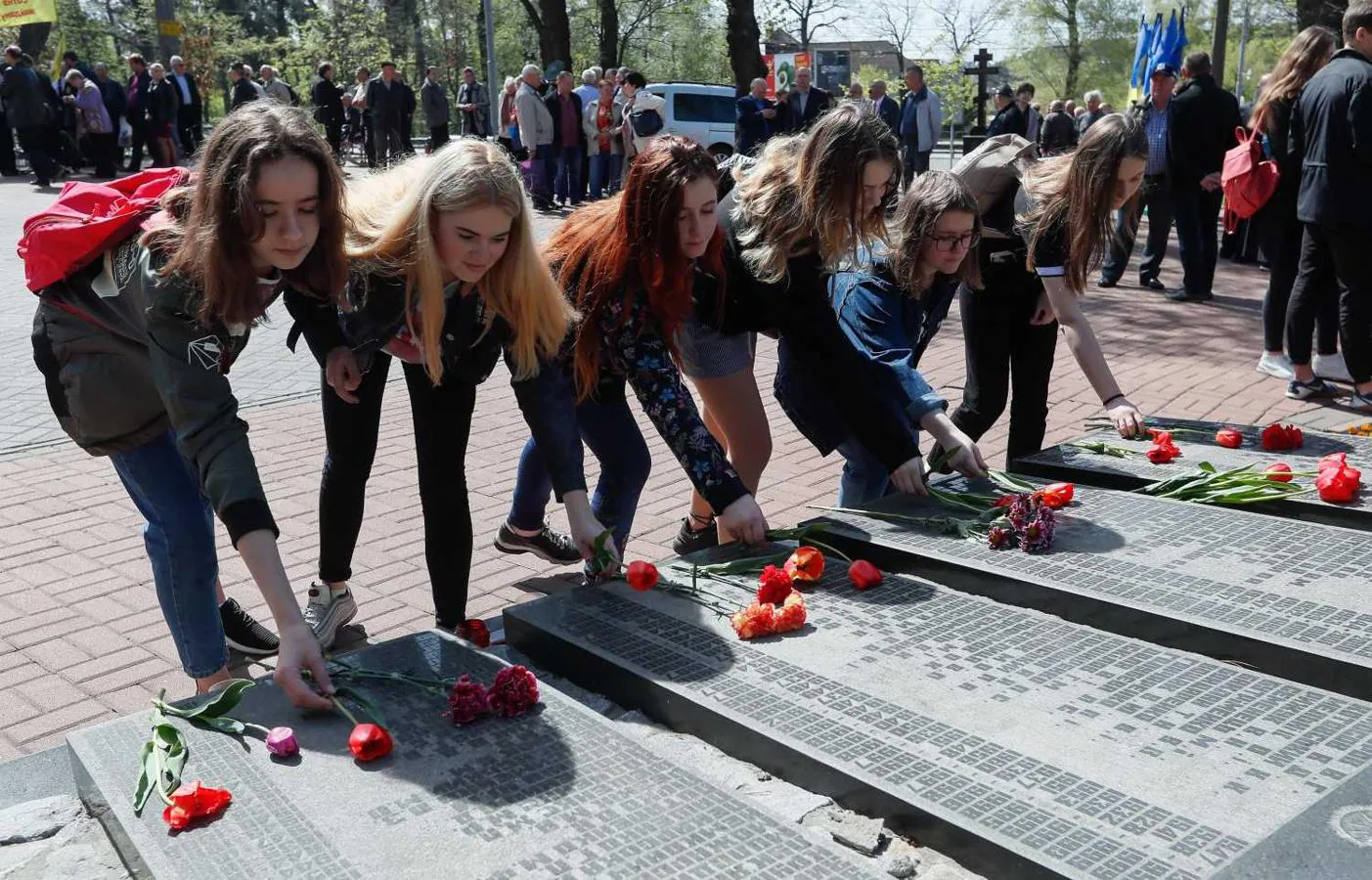 Jóvenes depositan flores ante el monumento que rinde homenaje a los que participaron en las labores de limpieza tras la tragedia en la central nuclear de Chernobil, en Kiev, Ucrania. Se cumplen 33 años del accidente nuclear, el más grave de la historia. 